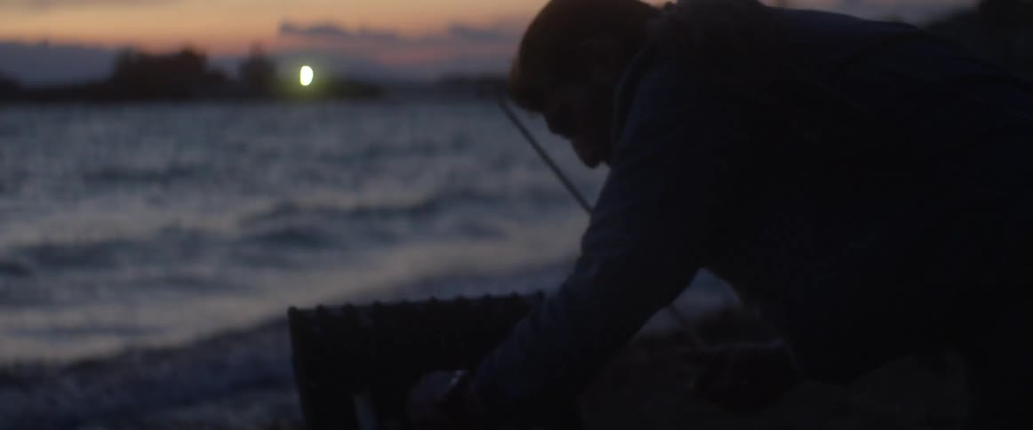 Man putting away fishing equipment at sunset