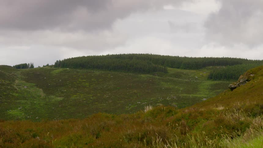 Timelapse of clouds passing over a green hill