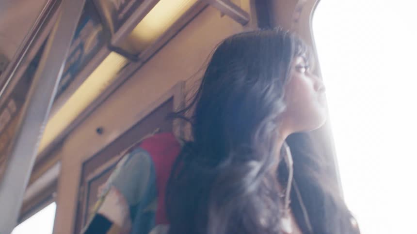 Woman with headphones next to the window of a moving train