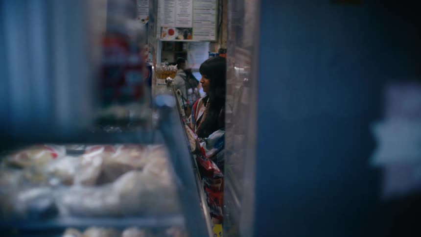 A young woman buying something at the counter of a bakery then heading to the exit