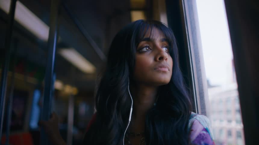A young woman looks out the window as she rides a subway train