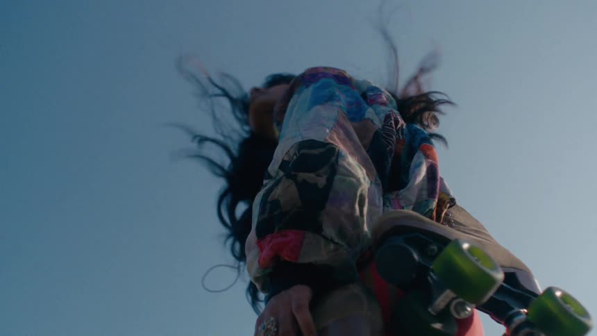 Female roller skater stands outdoors on a windy day with a roller skate