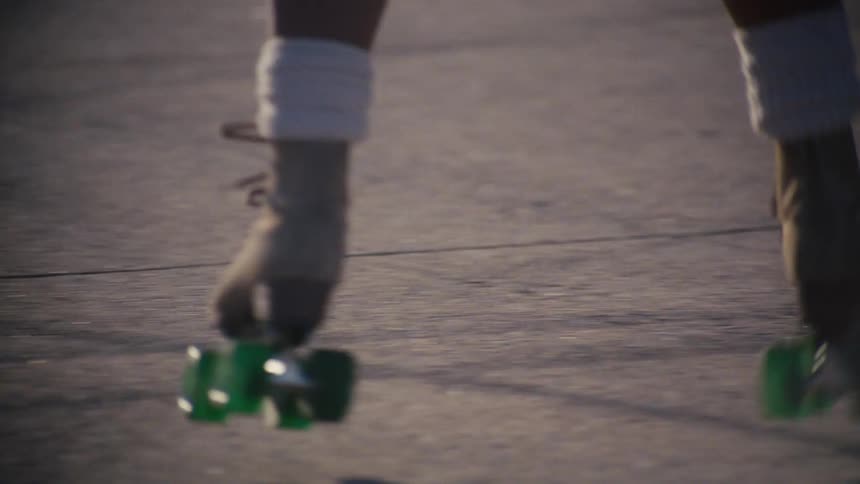 A person wearing green roller skates and the person takes a spin