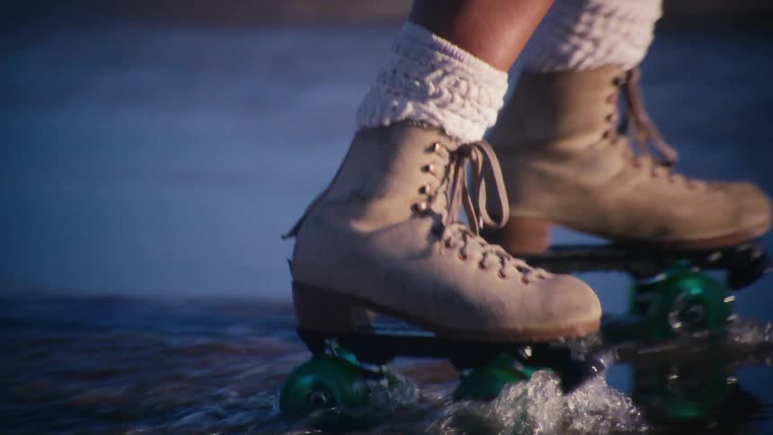 Legs of a woman crossing a puddle of water with roller skates