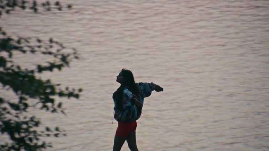 A woman stretches her arms out as she skates by the water