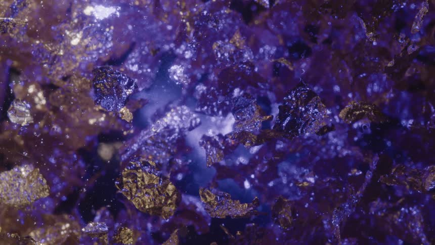 Abstract golden flakes floating against a purple light