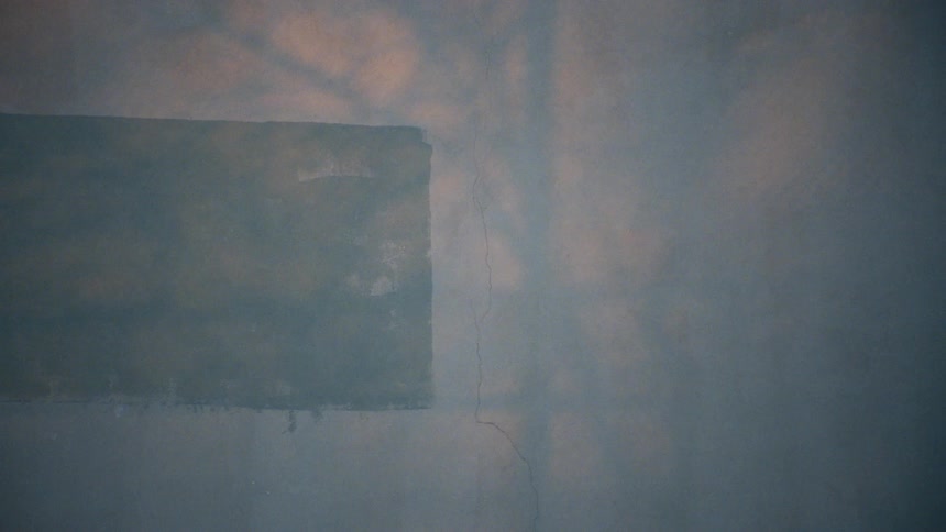 Woman in a colorful blouse walking past a white cracked wall