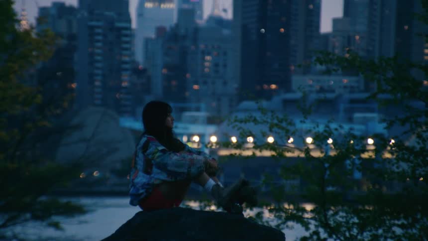 A young woman with roller skates sitting on a rock in a city park