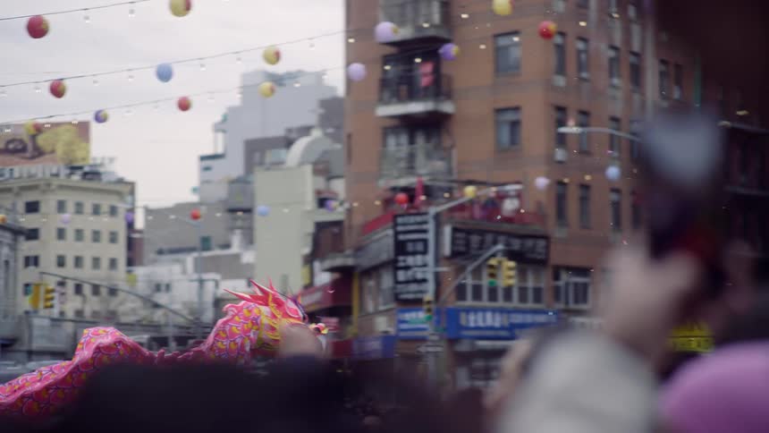 Festival with a crowd of people on the streets of a city with a chinese dragon passing by