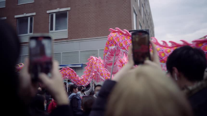 A festival where a red cloth dragon is passed around among people who are watching and recording videos