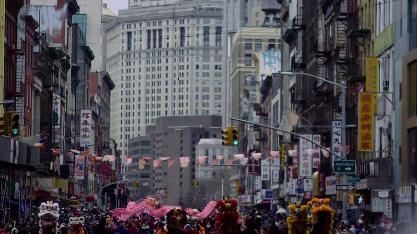 A giant parade involving large dragon dolls unfolding in a downtown city street