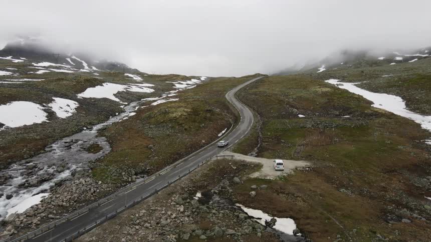 A car drives down a winding road through a mountain pass