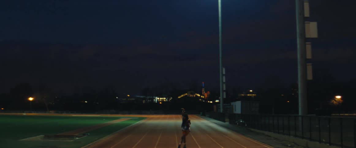 Woman rollerblading on a running track at night