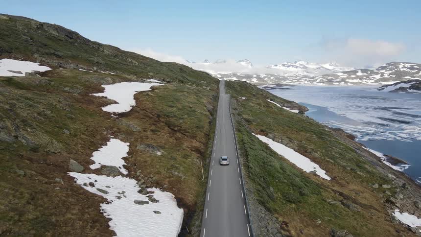 Aerial view of two cars driving down a highway near a glacier