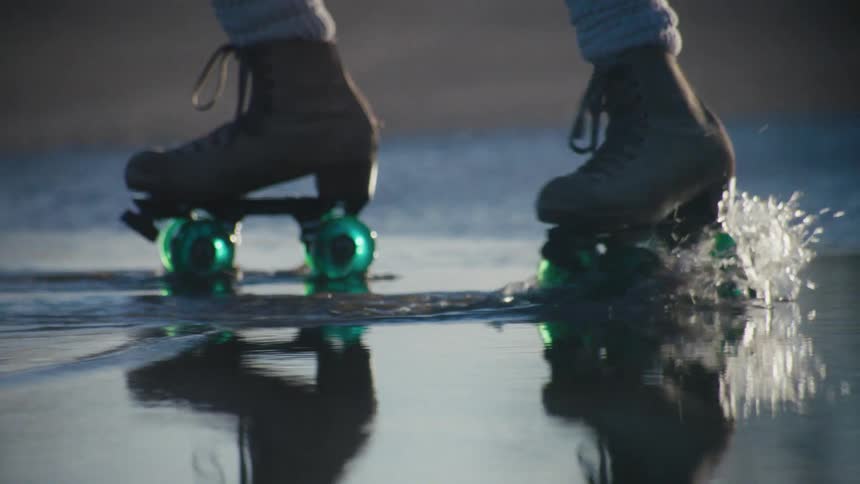 A woman roller skates through a puddle