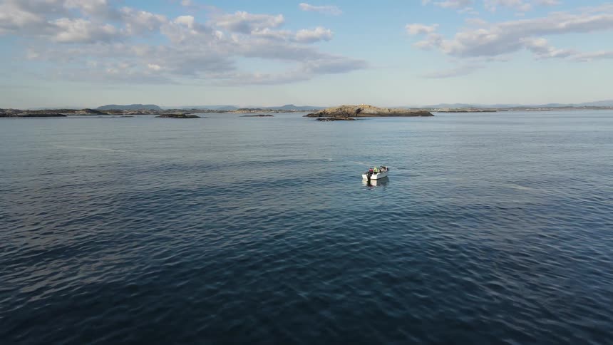 People ride in boat bobbing on ocean with islands in the background