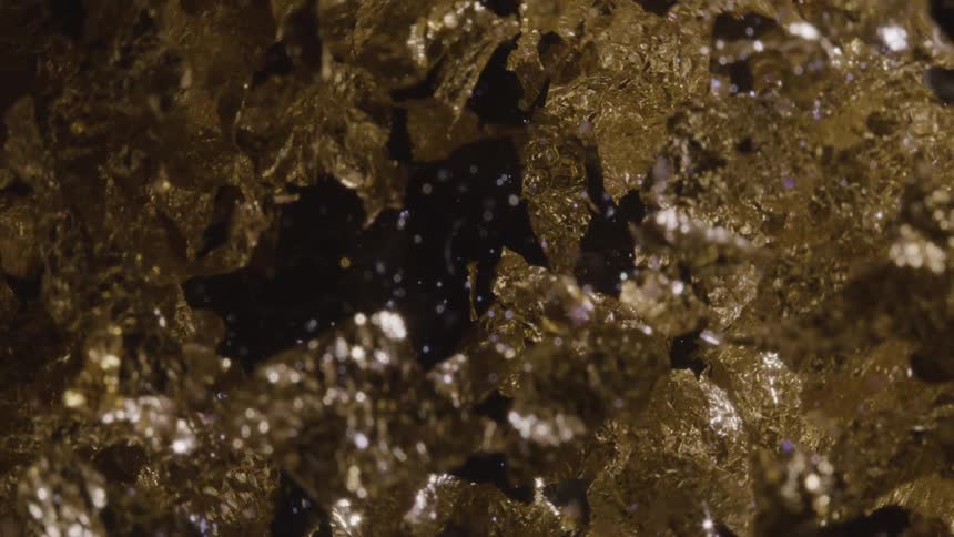 A pile of gold leaf flakes scattered across a black background