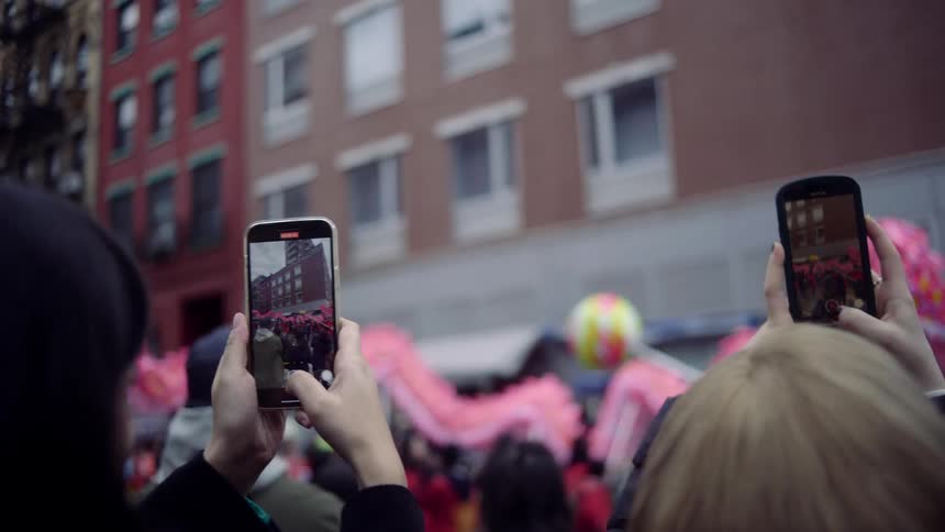 People are filming the parade with their cell phones