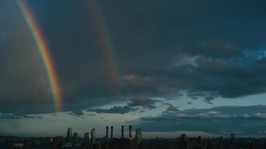 Panorama of the silhouette of a metropolis with skyscrapers and a rainbow on a cloudy day