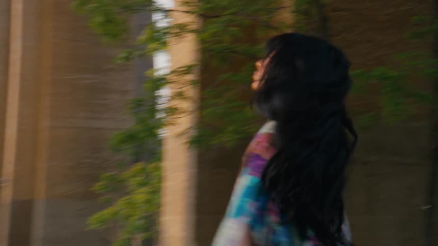 A woman riding a roller is spinning while walking on an asphalt street and has headphones on white