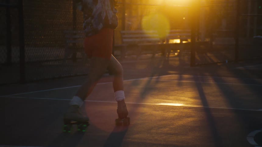 A woman dancing on roller skates on a street basketball court