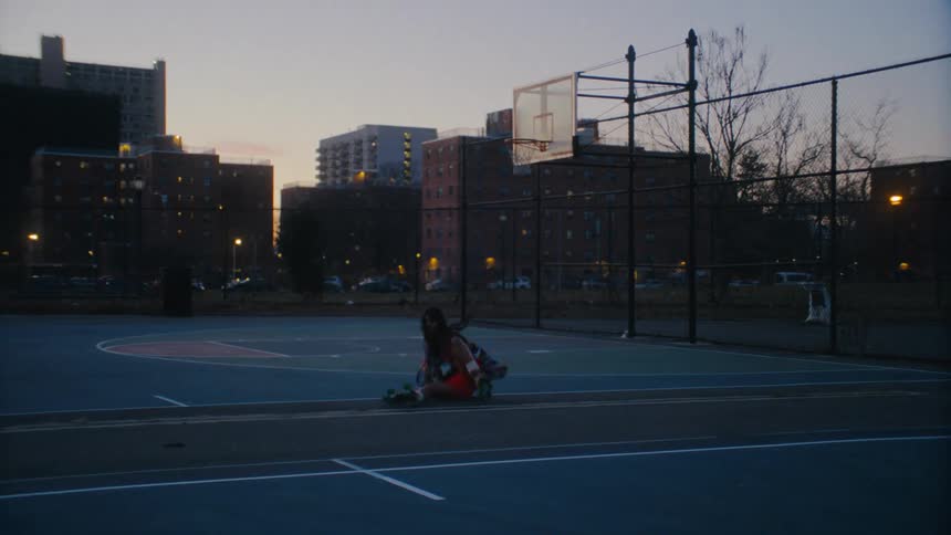 A woman riding a roller on a basketball court and she falls backwards