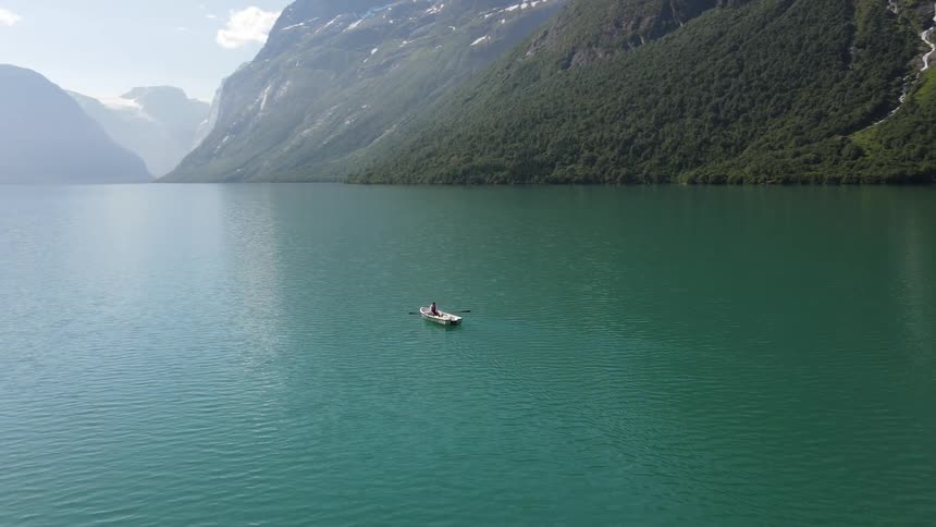 Aerial view of a small boat in the center of a lake in the mountains
