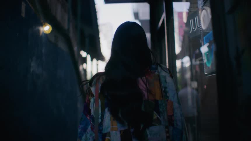 A woman is walking on the sidewalk in the city