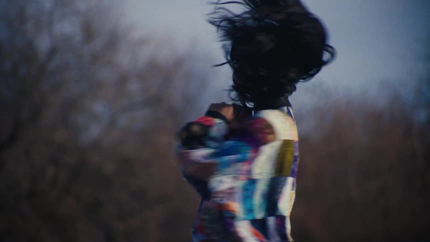 Woman with a colorful blouse twirling in an openair environment