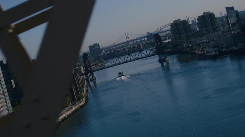 A boat sailing on a river that passes under a bridge in a city