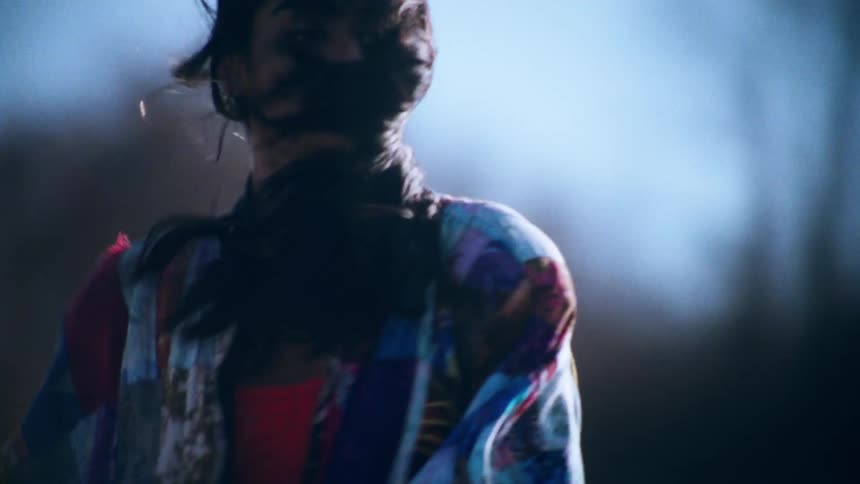 A woman has her back turned and then she turns and starts walking forward