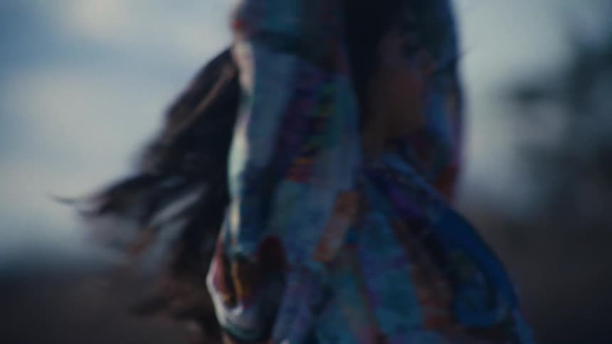 A young woman listening to music and dancing outside sliding as if on rollerskates