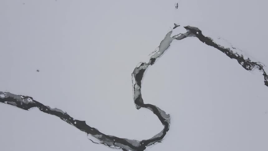 Cracked crevices with snowcovered river paths
