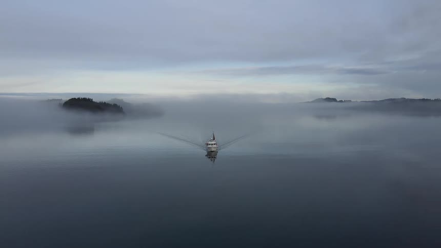 Aerial panorama of a boat sailing on an ocean on a cloudy morning