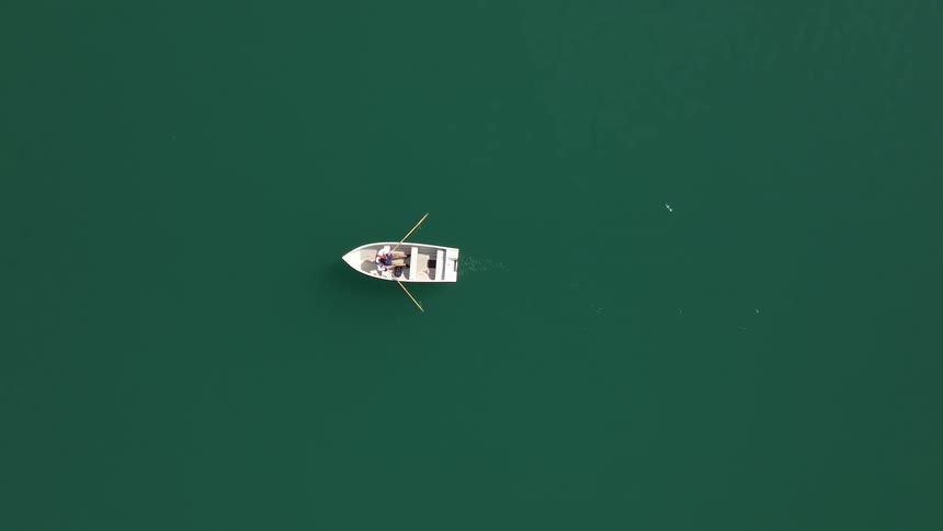 A person rows their boat in the calm water