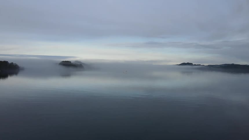 Landscape of an extensive calm lake on a cloudy day at dawn