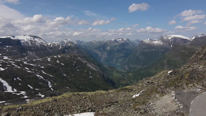 Aerial landscape of a mountainous valley with peaks with snow and a blue sky with clouds
