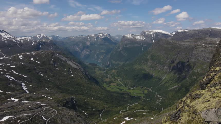 Aerial panorama of a valley and mountain ranges with snowcapped peaks