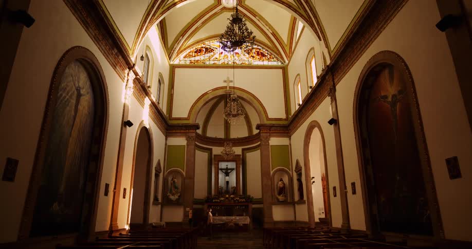 Sunlight streams through a colorful stained glass window in a church