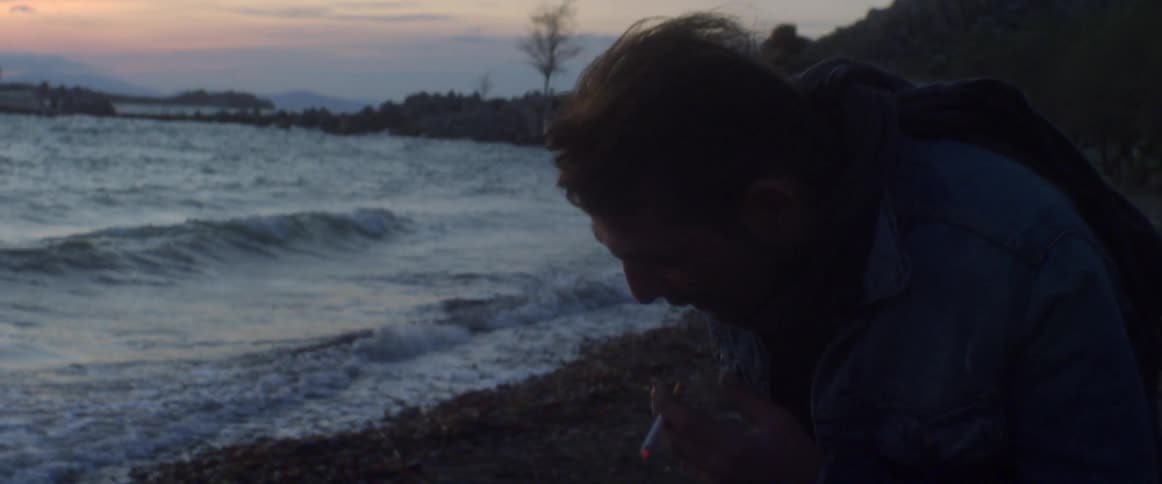 Man smoking a cigarette at sunset by the coast