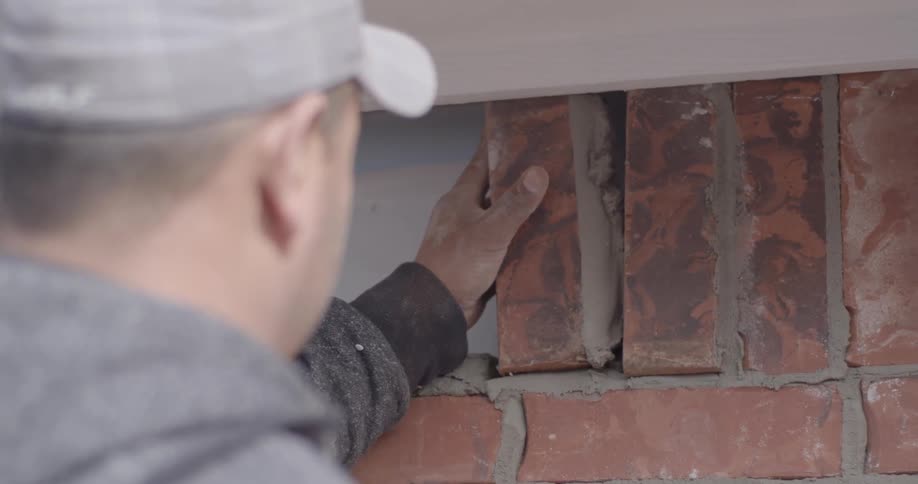 A construction worker placing a brick into a wall