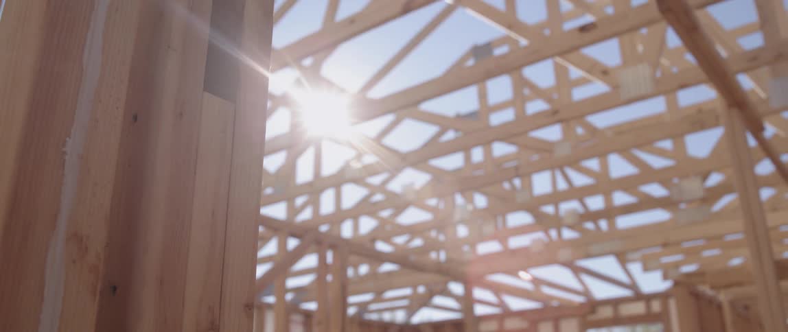 The sun shines through building construction framing on a sunny day