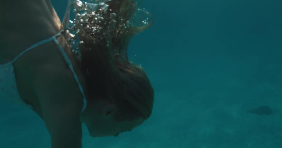 Lighthaired woman diving in the ocean