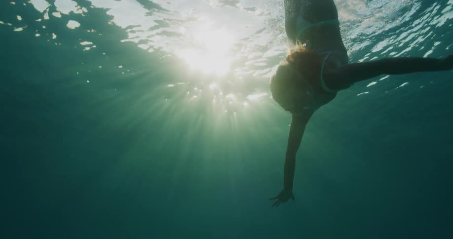 A woman dives and swims underwater