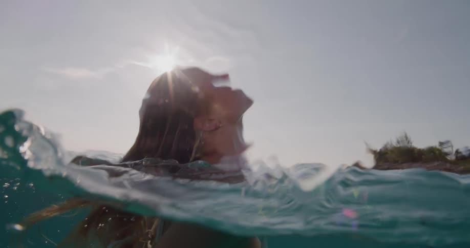 A young woman swims through the water then surfaces