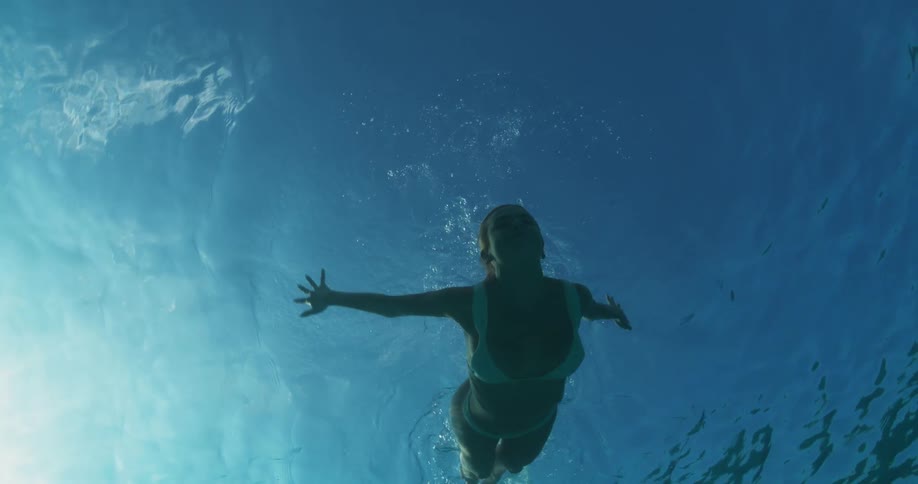 Woman in a white bikini diving in an ocean