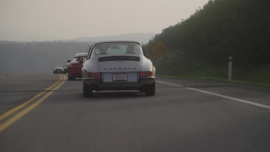 A row of sports cars travel in a line on the highway