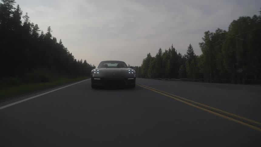 Sports cars traveling along a paved road with trees around