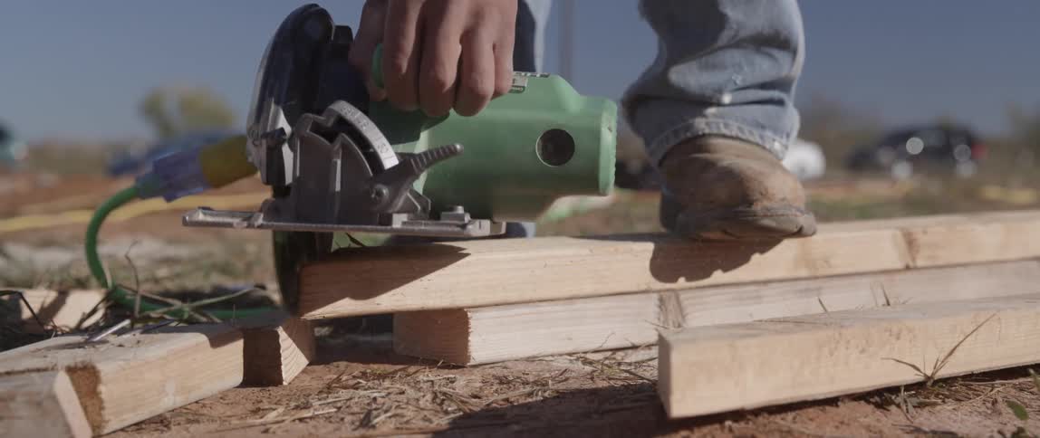 A person cuts off the end of a board with a skilsaw