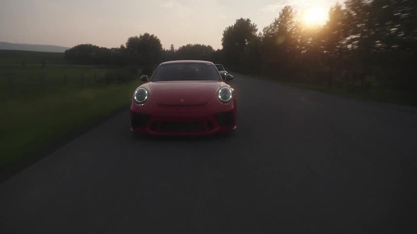 Late afternoon with the sun on the horizon and sports vehicles traveling along a road